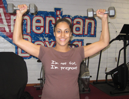 Gina Reyes personal trainer holds weights while pregnant.